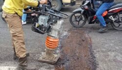 Petugas DPUPR melakukan pemadatan aspal sebagai langkah perbaikan pada jalan berlubang di Jalan Pintu Air 10.