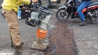 Petugas DPUPR melakukan pemadatan aspal sebagai langkah perbaikan pada jalan berlubang di Jalan Pintu Air 10.