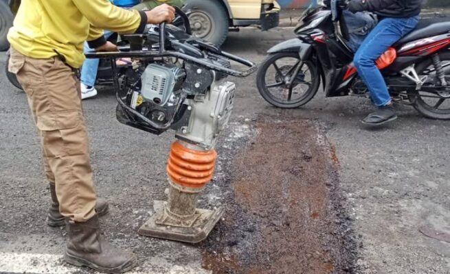Petugas DPUPR melakukan pemadatan aspal sebagai langkah perbaikan pada jalan berlubang di Jalan Pintu Air 10.